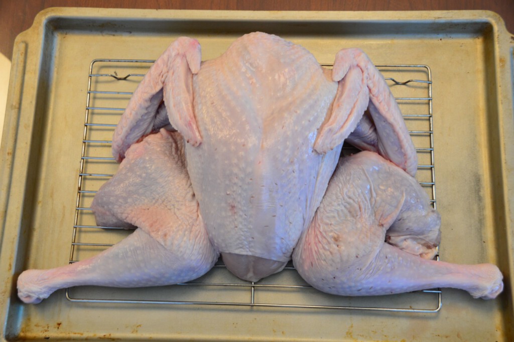 Raw spatchcock turkey on rack and pan